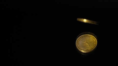 1 Euro coin falls on a black mirror