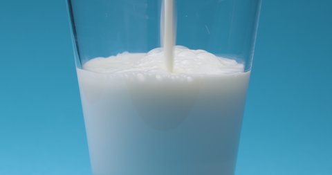 Milk is poured into a milk glass on a blue background.