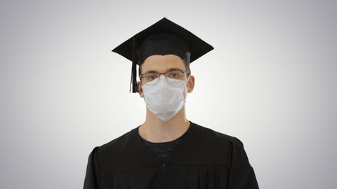 Graduate student in a medical mask walking on gradient background.