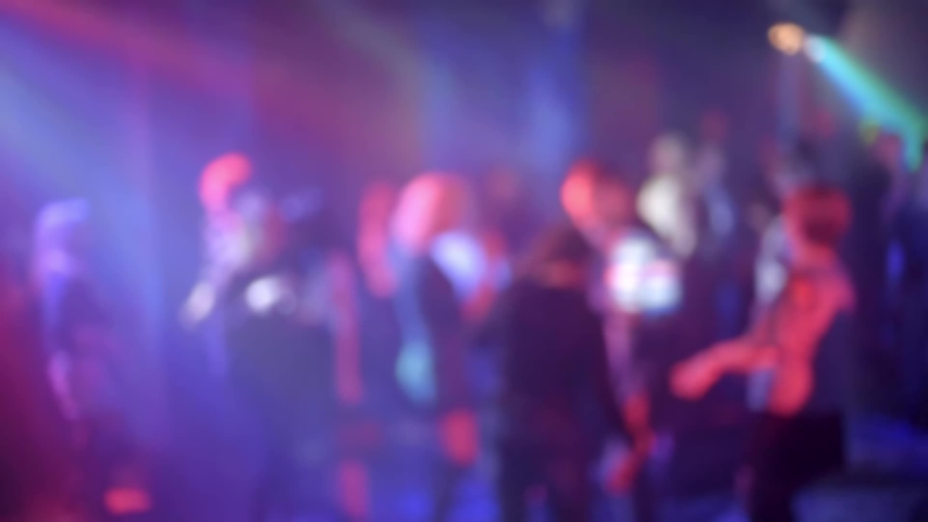 crowd of people dancing on the dance floor of a night club under the light of colored spotlights and lasers. Blurred silhouettes Royalty-Free Stock Footage #1052723297