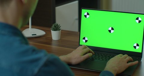 Male Video Editor Works on His Personal Computer with Green Screen Mock Up Display.