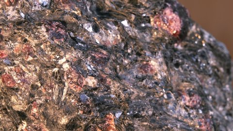Garnet Mica-Schist sample. Almandine-garnets Crystals interspersed in a massive piece of shale rock. Background image of rough rock of dark and dark red color