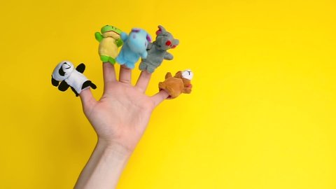 Animals zoo puppet dolls theater. Hand wearing finger puppets: elephant, frog, dog, rabbit, hippo,bear, panda. animal finger puppets show on yellow background. quarantine fun. template mock up.