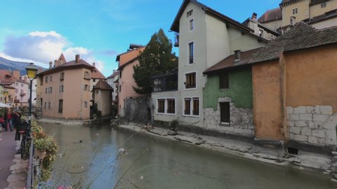 Annecy / France - October 5, 2019: DOLLY SHOT - Thiou canal, bridge Passage de l'Ile, bank, the Quai de l'Eveche, Ile palace (former prisons) and houses with colorful facades in the old town.