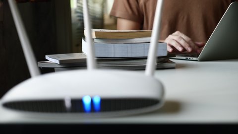 Close up of a wireless router and a man using laptop on the table