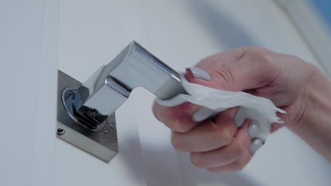 Disinfection, protection, prevention, housework, COVID 19, coronavirus, safety, sanitation concept. Slow motion: woman cleaning door handle with antiseptic disinfectant wet wipe - low angle close up