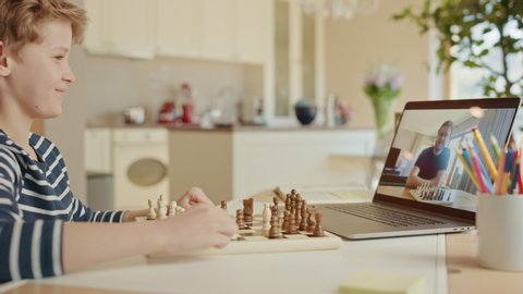 Brilliant Little Boy Playing Chess with His Chess Master, Uses Laptop for Video Call. Child Learns how To Play Chess Through Internet. Remote Online Education,  E-Education,  Distance Learning, Homesc