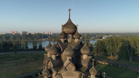 Flight around traditional orthodox old Church of Intercession wooden architecture Russia. Petersburg Nevsky park religious attraction. No nail reconstruction. Contrast old and modern cityscape. Sunset