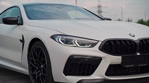 ROSTOV-ON-DON, RUSSIA - MAY 7, 2020: brand new matte white BMW M8 Competition Coupé sports car in empty car parking lot on cloudy day  - close-up of front lights.