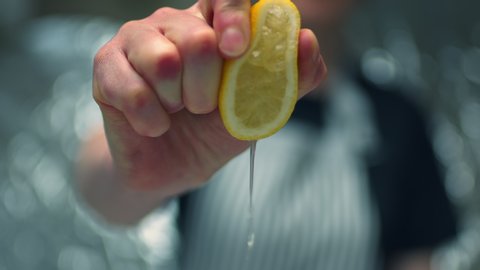 Close-up slow motion of a woman hand chef, squeezing fresh lemon making juice on a macro bokeh background