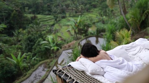 Travel Influencer and blogger relaxing in a property in Bali overlooking rice fields and green tropical landscape