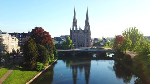 Aerial top view of the St. Paul's Church in Strasbourg, France. Drone flying over beautiful river, surrounded by green and red trees