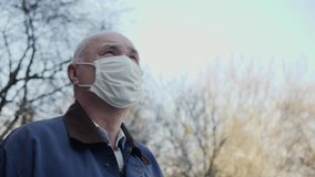 Portrait of elderly man with handmade mask on his face to protect himself from coronavirus pandemic. Close-up of man standing outdoors looking up at the sky. Concept of hope, faith, health and safety - Powered by Shutterstock - Get 15% off with code: PIKWIZARD15