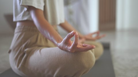 Close up of woman hands sitting in lotus pose and meditate practicing yoga. Calmness girl relaxing mind by meditation in modern living room