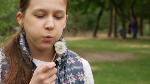 Beautiful Girl Blowing Dandelions On Summer Day