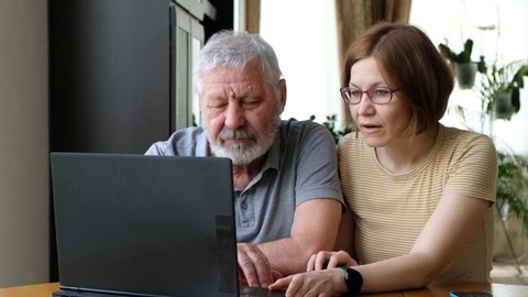 Happy senior elder father grandfather and adult grown daughter, helping him with computer