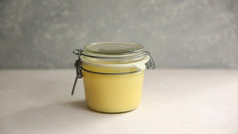 Ghee or melted butter in a jar on wooden table. get a silver spoon from a can