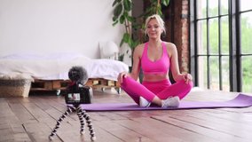 Social distance. A young woman fitness instructor records a tutorial on home workouts on camera.