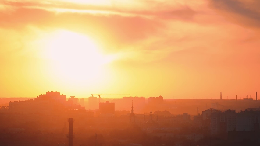 Sunset over the city close-up. Silhouettes of buildings and rays of the sun radiate from the Church at sunset. City in a haze at sunset
