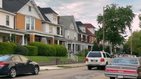 A daytime summer exterior establishing shot of typical rust belt middle class homes in a residential neighborhood of a small New England town. Pittsburgh suburbs.  	