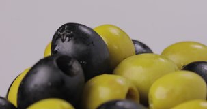 Green olives with black olives spin on a white background.  macro video. Three shots.
