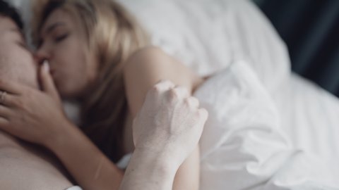 Sweet couple petting in bed in bokeh. Marriage, family, love, sex concept. Filmed on REd 4k, 10 bit color