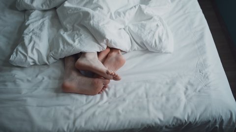 Couple petting in bed. Only feet in frame. Marriage, family, love, sex concept. Filmed on REd 4k, 10 bit color