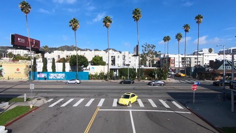 Los Angelles , CA / United States - 01 23 2020: Slow-motion aerial approach over yellow VW Bug facing Sunset Boulevard Traffic in Hollywood, CA