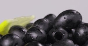 Black olives with lemon and without lemon spin in a frame on a white background. macro video. two shots.
