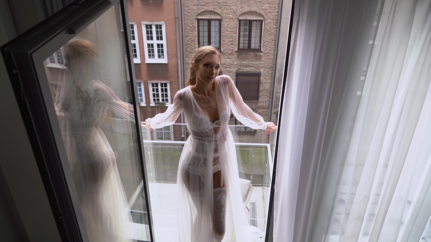 Bride in a white dress opening the window. Wedding preparations, morning bride in boudoir dressing