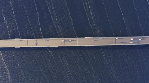 High spinning aerial overhead shot above the Tasman bridge over the Derwent river in Tasmania Australia, with traffic, cars and trucks, crossing in morning light, whites streaks on the water