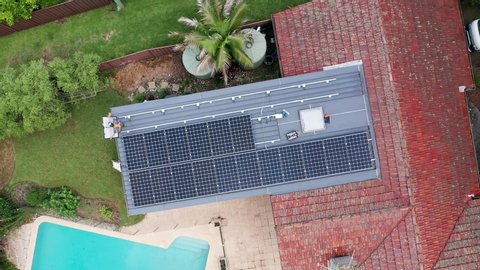 Sydney, Australia - March 9 2020: A direct overhead aerial shot of solar panel installation - trades men installing solar panels onto pitched tiled roof and flat roof of a residential suburban home