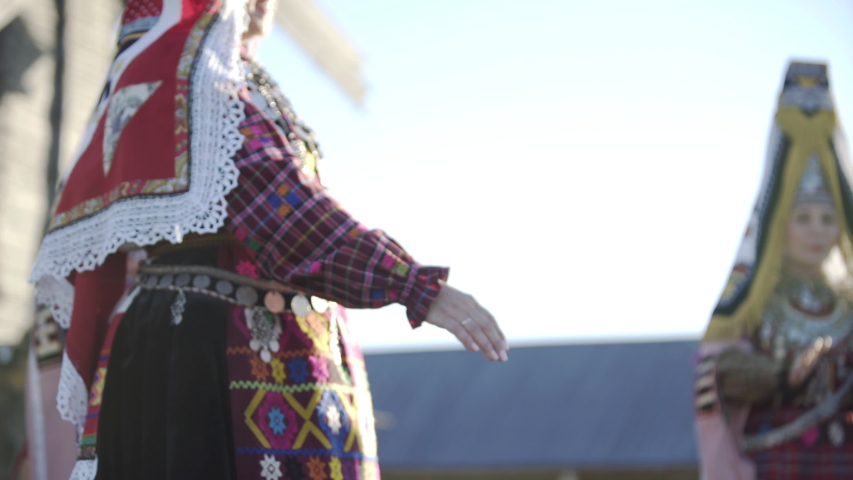 People in traditional russian clothes dancing outdoor on traditional antique wooden windmill background. Group of happy people wearing national Finno-Ugric clothes. Royalty-Free Stock Footage #1052777897