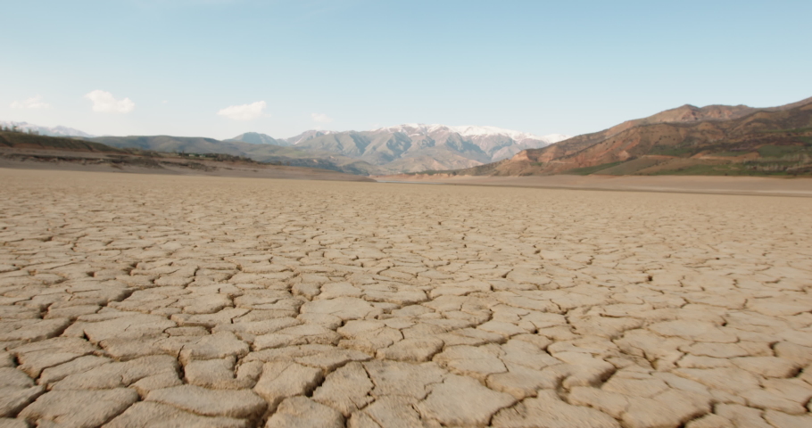 Dynamic shot of cracked soil ground of dried lake or river in mountains. Land destroyed by erosion and global warming - ecological issues concept 4k footage | Shutterstock HD Video #1052779625