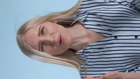 Desperate and angry woman spreading her hands to the sides and crying with blue background. She asking why. Video with Vertical Screen Orientation 9:16