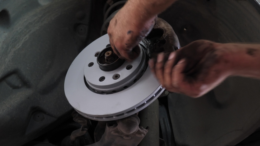 A car mechanic changing the disc brakes, backing plates and brake pads on a car