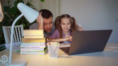 sleepy dad helps daughter with fun online lessons on the laptop, distance learning. insulation, stay home. quarantine and epidemic. a lot of homework.