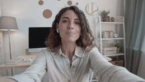 Medium shot portrait of Caucasian businesswoman with curly hair staying home and discussing charts with business partner by video link