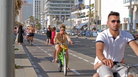 Tel Aviv, Israel - May 4, 2019: Static shot of the beach in Tel Aviv. Bicycle tracks on the embankment of Tel Aviv. People ride electroscooters and bicycles. 4K Footage .