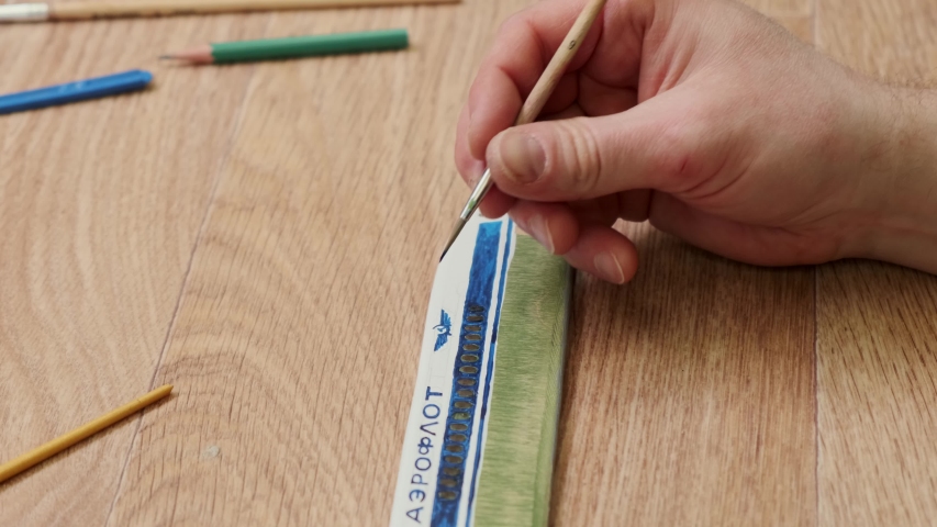 mature person draws logo on passenger jetliner part sitting at table in Sunday school classroom closeup slow motion