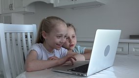 European two happy kids sitting at laptop studying online at home, social distancing, homeschooling education, covid-19 coronavirus concept.