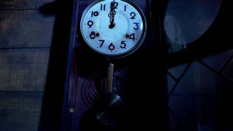 Close up of antique pendulum wall clock on midnight 