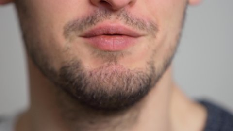 Close-up of a man’s talking mouth. Unshaven guy says. The lower part of the speaking young male face.