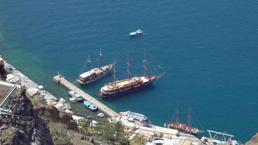 An ancient port in the capital of Santorini, Fira, with a tourist yacht at the pier. Greece