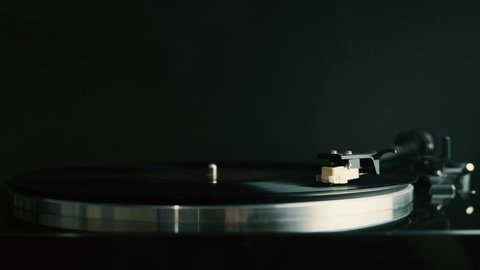 turntable plays vinyl disk on black background