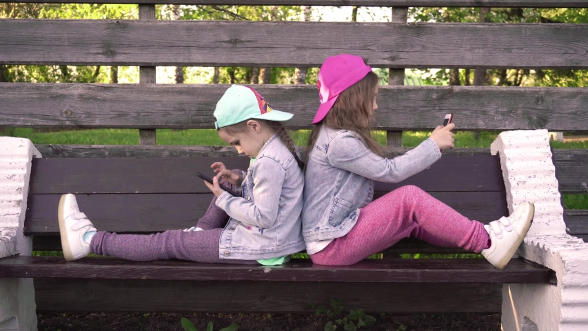 Two little girls make selphy and play mobile games, sisters are watching on the smartphone screen, kids are playing online