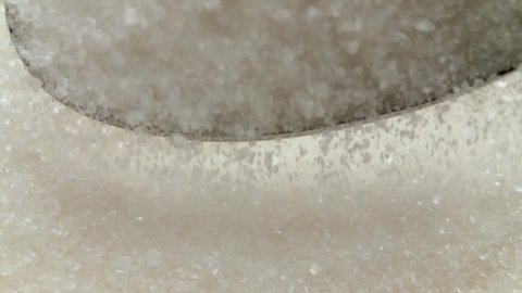 White sugar macro moves with a spoon.