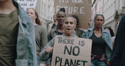 Group of protestors marching on the streets with signs and chanting. Activists protesting against pollution and global warming.
