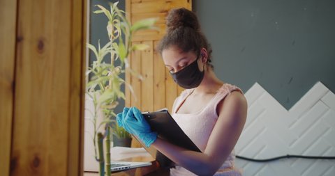 young african american woman wearing medical mask during remotely work at home due to coronavirus pandemic. Stay home remotely office coronavirus social distancing Video de stock