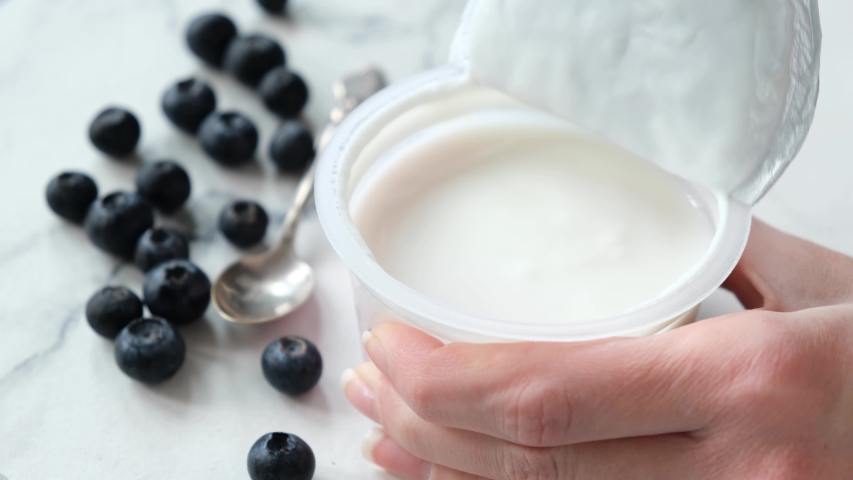 Opening plastic jar of plain greek yogurt. Store bought natural yogurt ready to eat | Shutterstock HD Video #1052825015